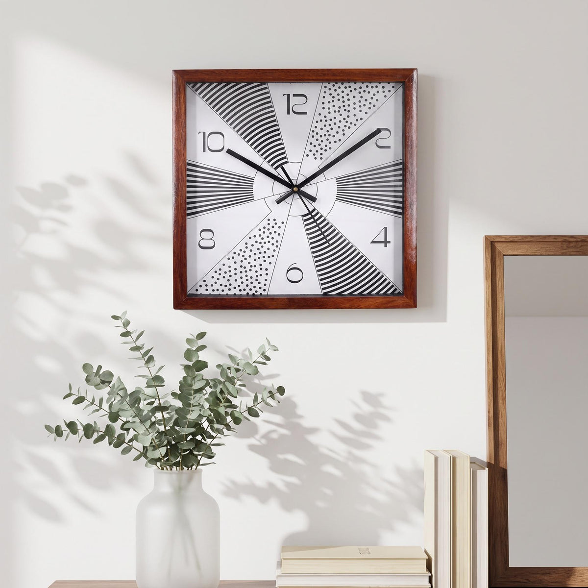 Black hands and thin second hand over the central hub of a sunburst wooden wall clock