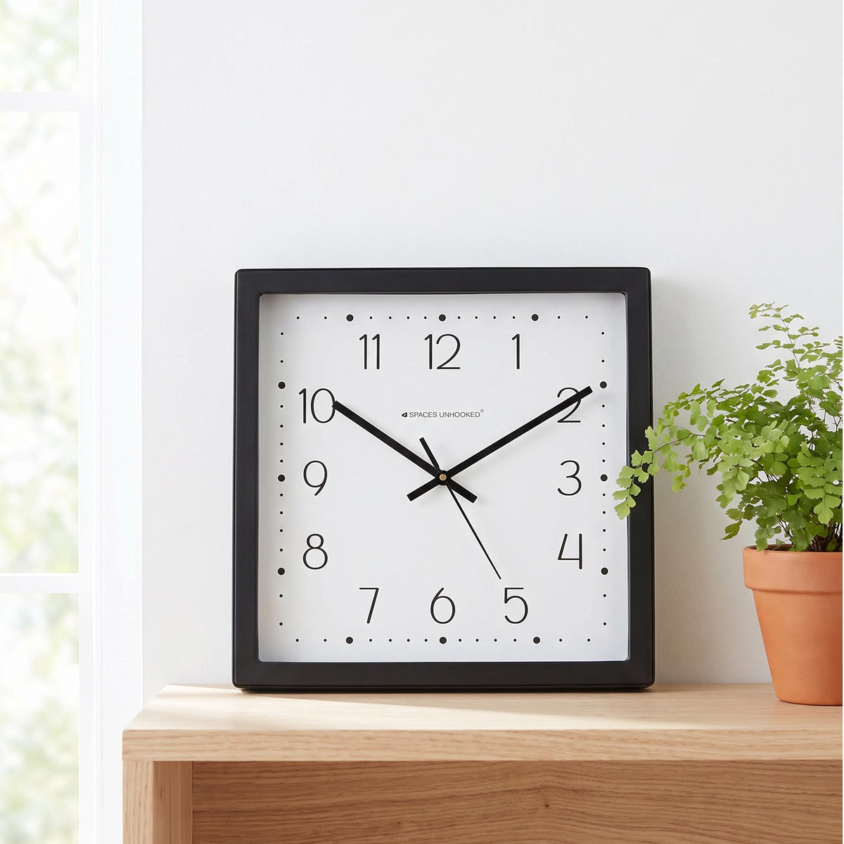 Black square wall clock frame with a clean even border, close-up view