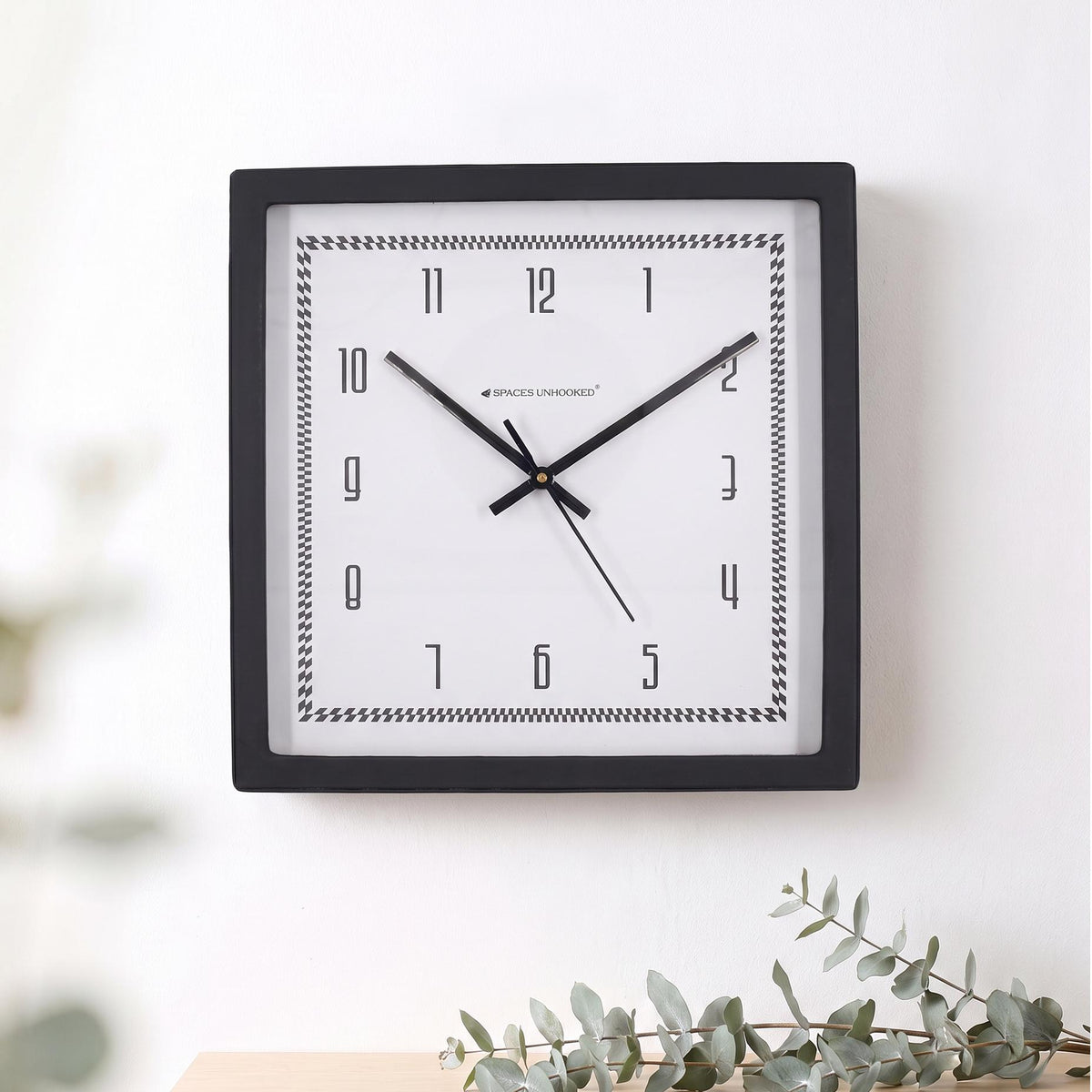 Black square frame and clear cover of a checked border wall clock, close-up view