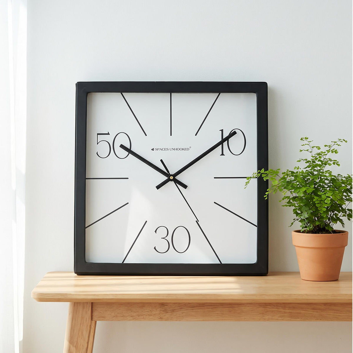 Black square frame and clear cover of a radial line wall clock, close-up view