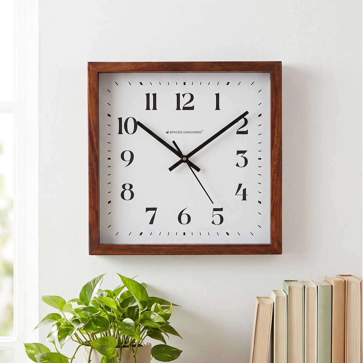 Warm brown wooden frame with visible grain and mitred corners on a square wall clock, close-up
