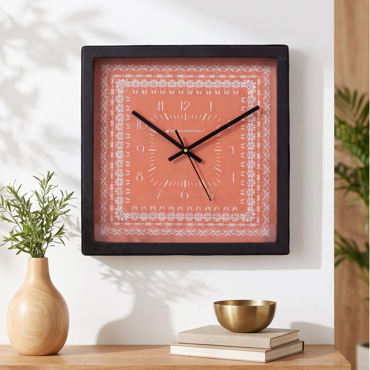 Black square frame and clear cover of a coral floral border wall clock, close-up view