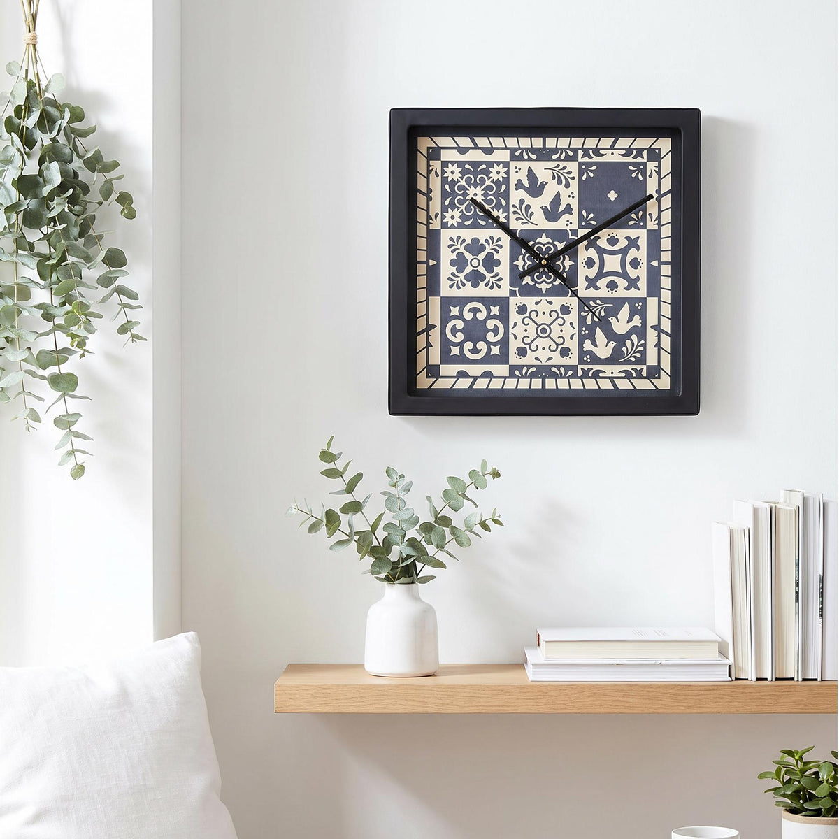 Black square frame and clear cover of a folk art tile wall clock, close-up view