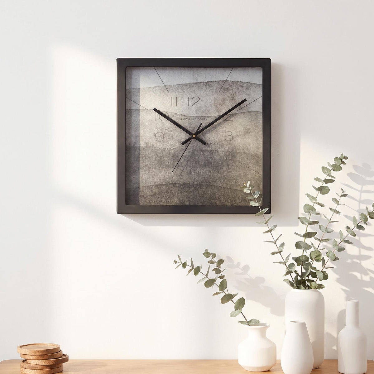 Black square frame and clear cover of a ash grey watercolour wall clock, close-up view