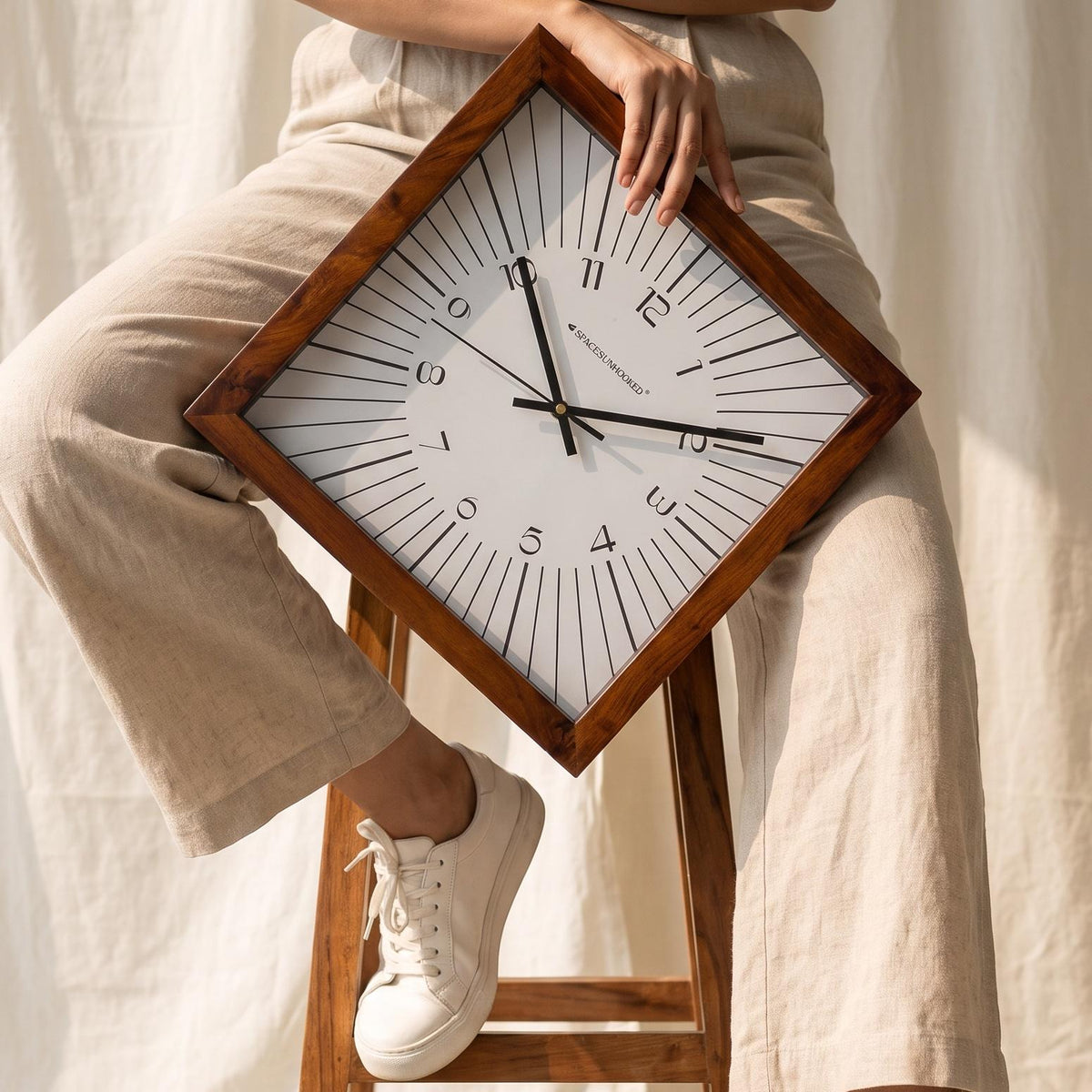 Close-up of fine black lines radiating across the white dial of a square wall clock