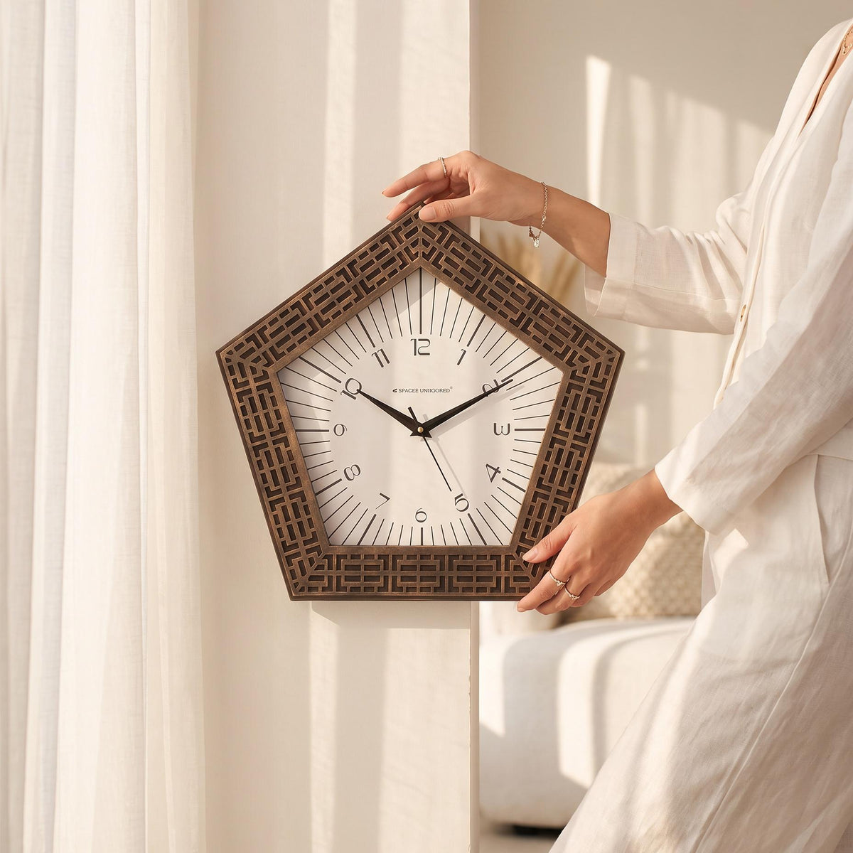 Close-up of slim numerals and fine radiating lines on a white pentagon clock dial