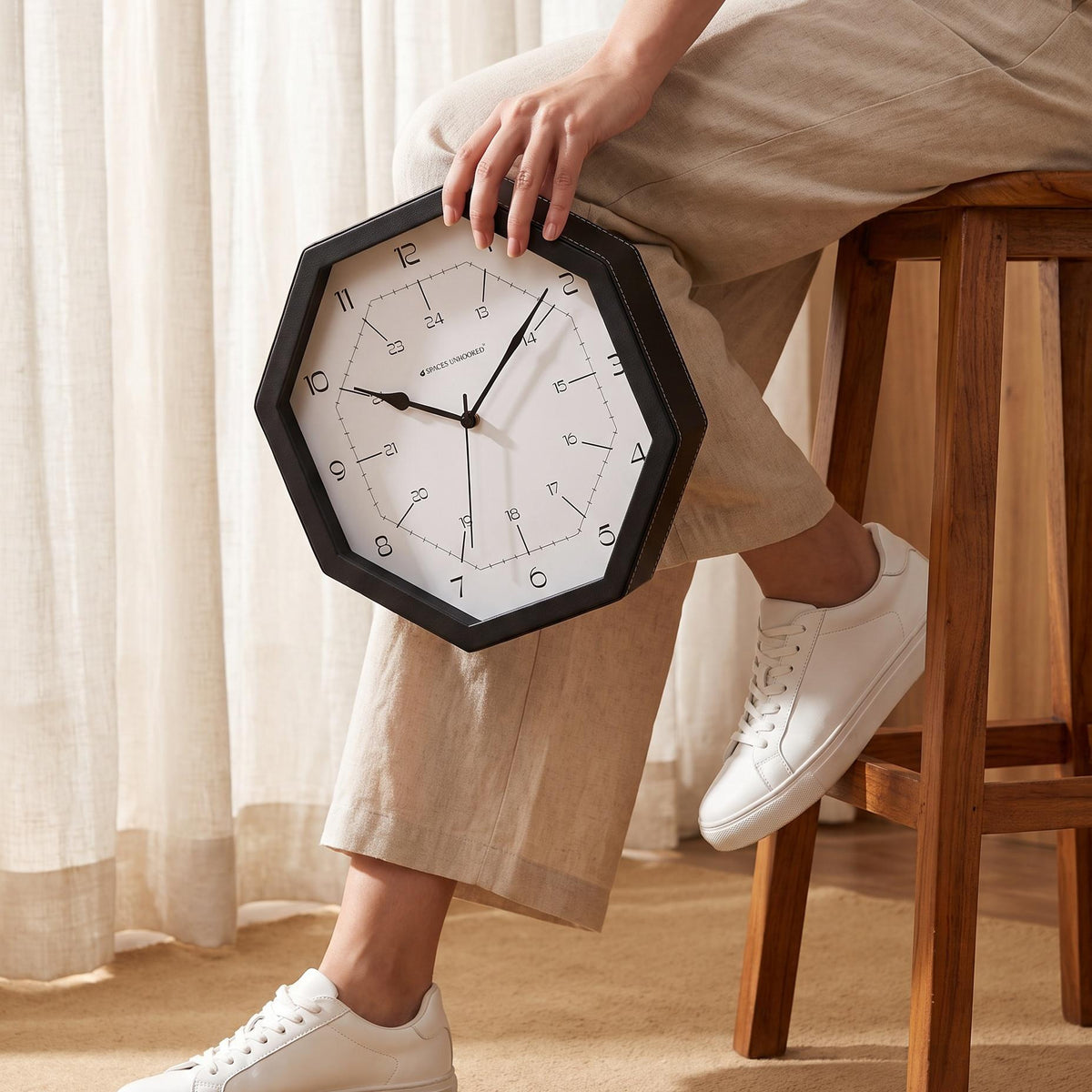 Octagonal black wall clock hanging above a sofa in a bright living room