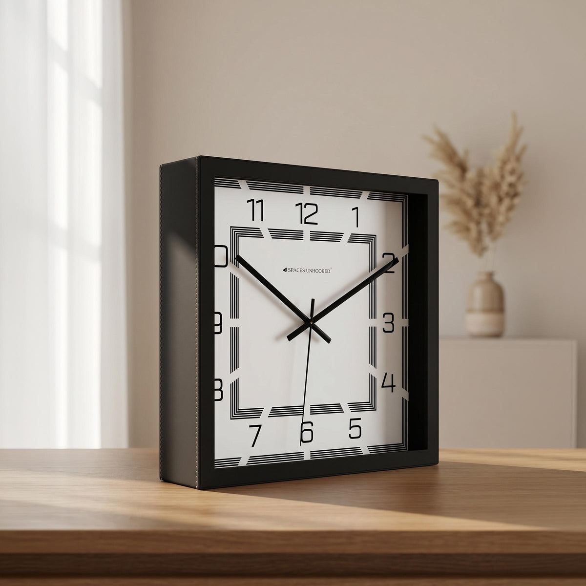Black square art deco wall clock in a home office above a work desk