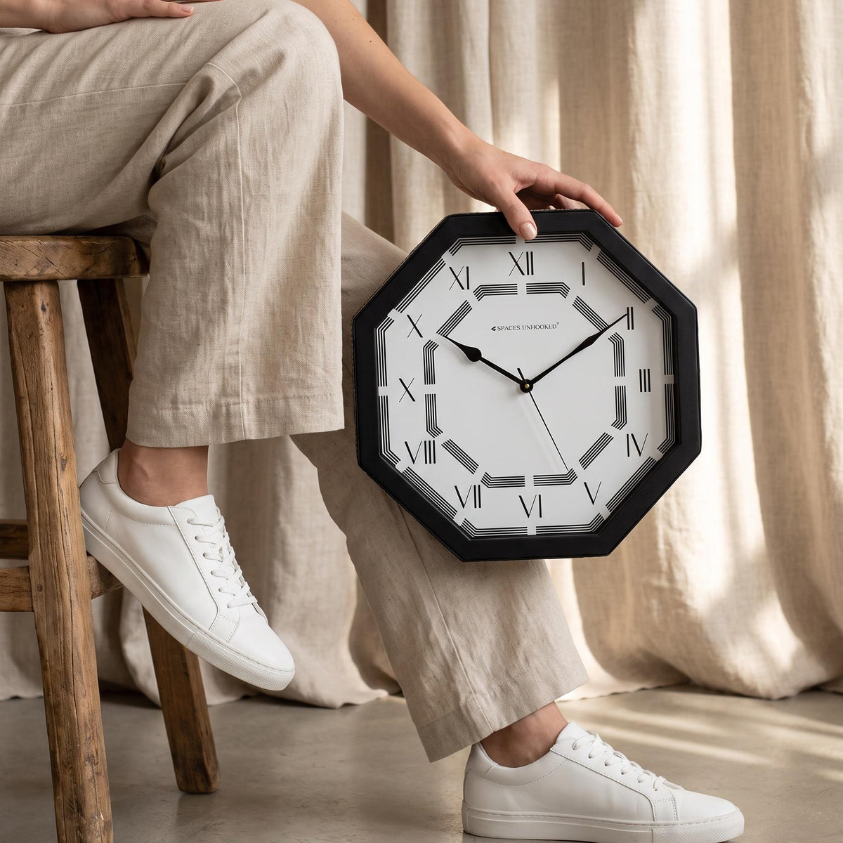 Roman numeral octagonal wall clock above a sideboard in a dining room