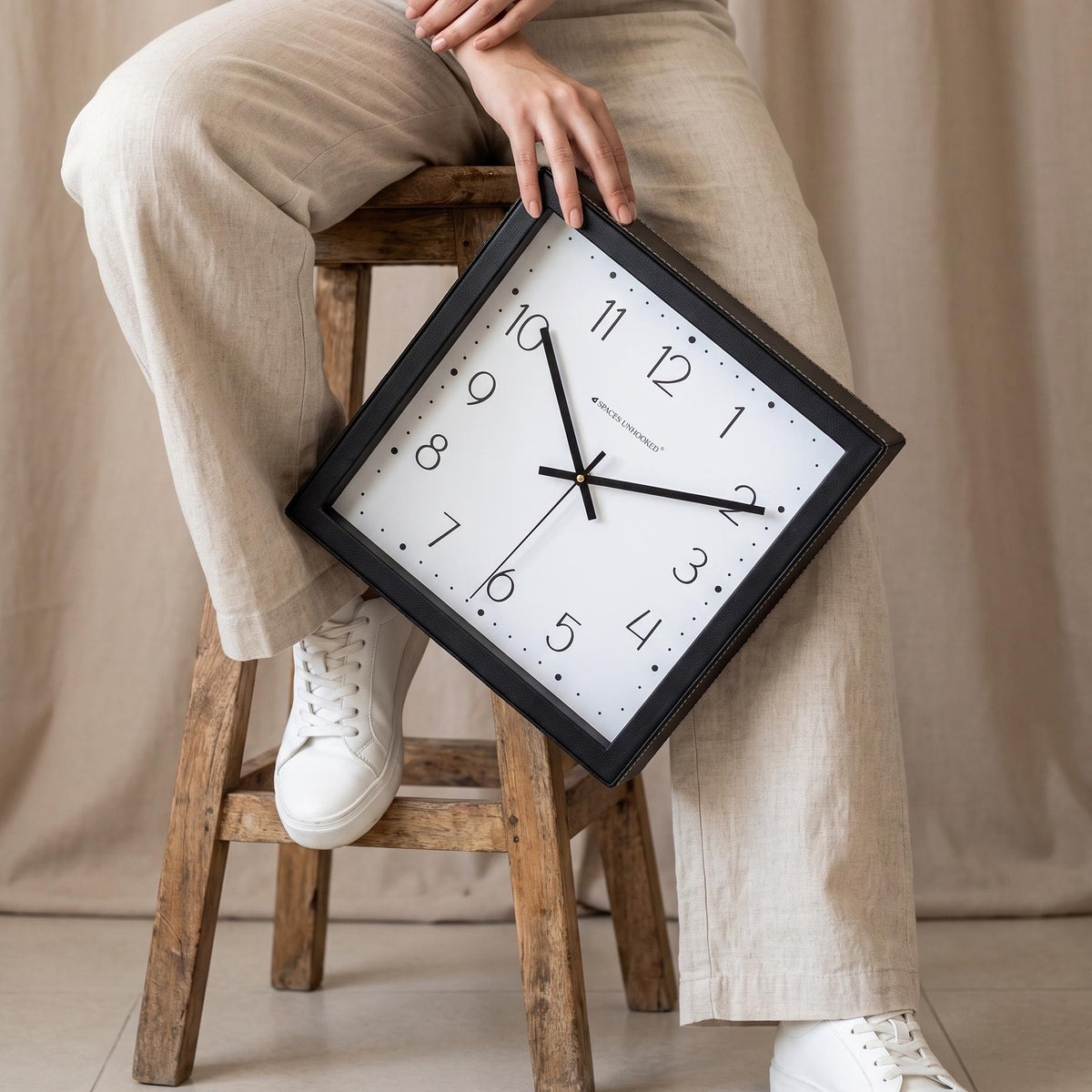 Square dotted dial wall clock hanging on a living room wall above a sofa