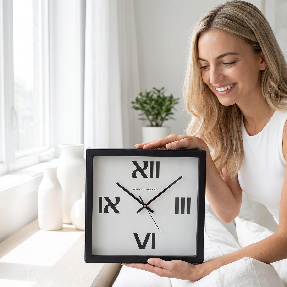 Bold roman numeral wall clock above a sofa in a bright living room