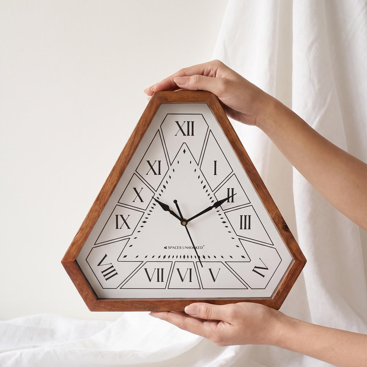 Roman numeral triangular wooden wall clock hanging above a dining sideboard in a warm home