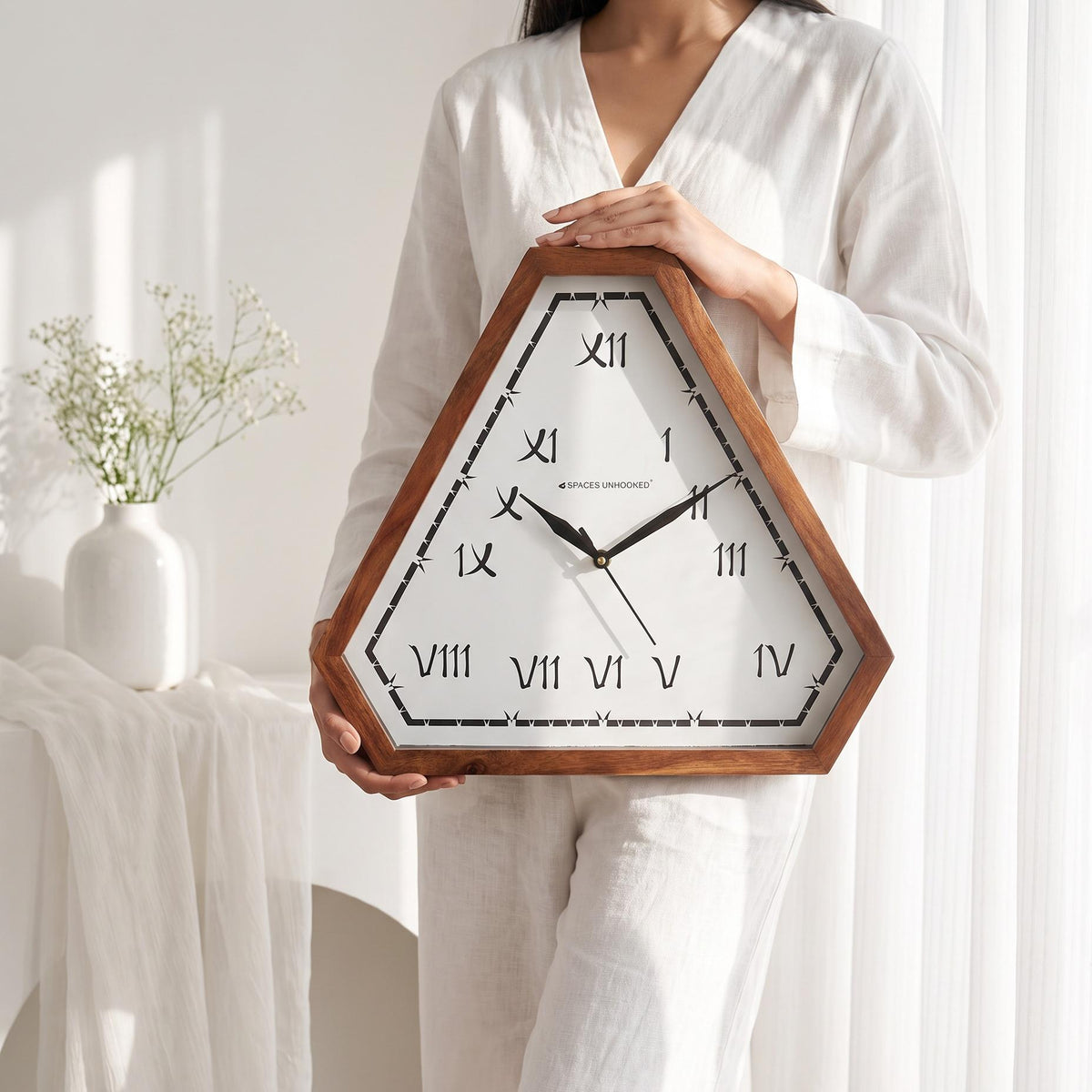 Brush Roman numeral triangular wall clock above a wooden console in a warm living room