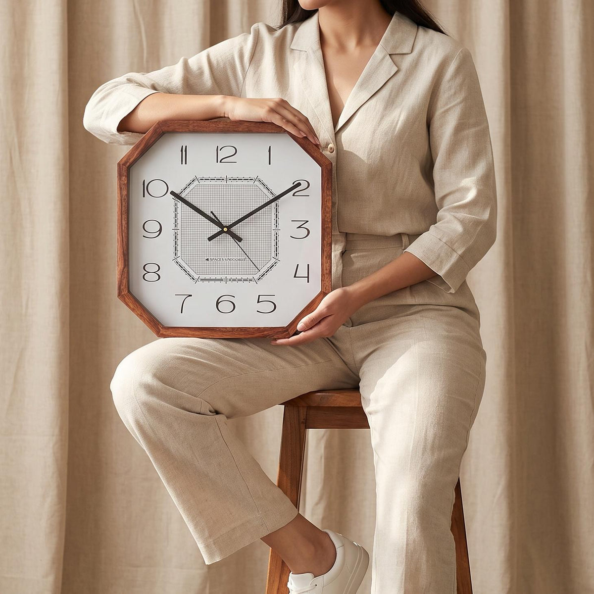 Art deco cut-corner wooden wall clock on a plain living room wall above a sofa with brass lamps