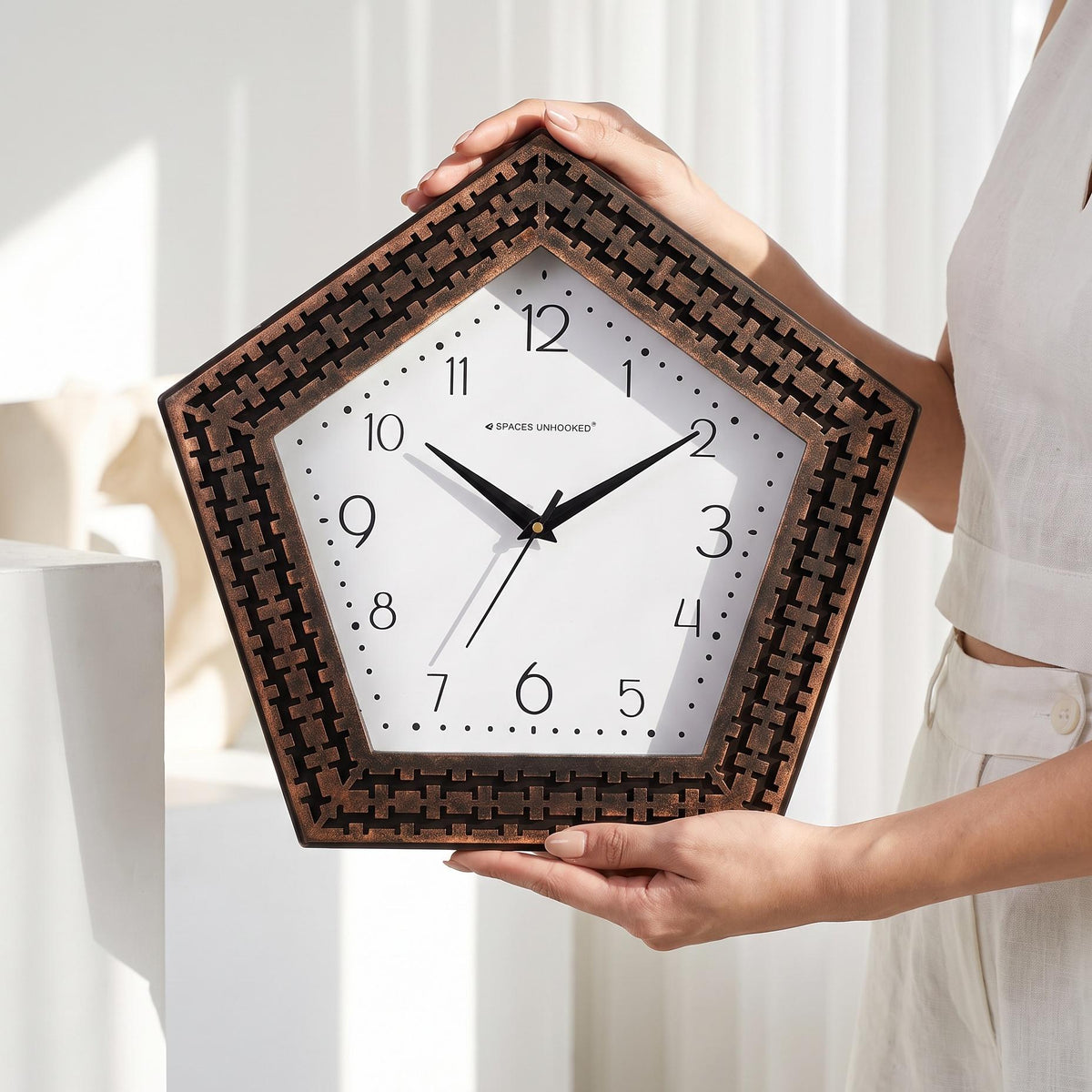 Close-up of bold numerals and a dotted minute track on a white pentagon clock dial
