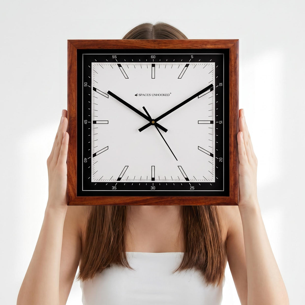 Square wooden wall clock with black bezel above a work desk in a modern home office