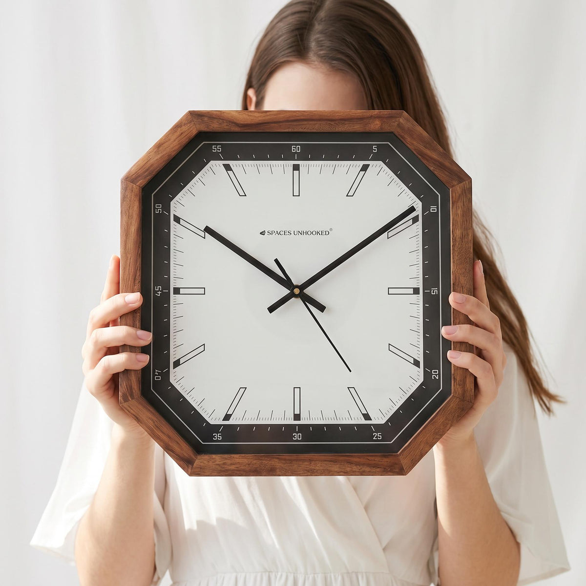 Cut-corner wooden wall clock with black bezel above a work desk in a modern home office