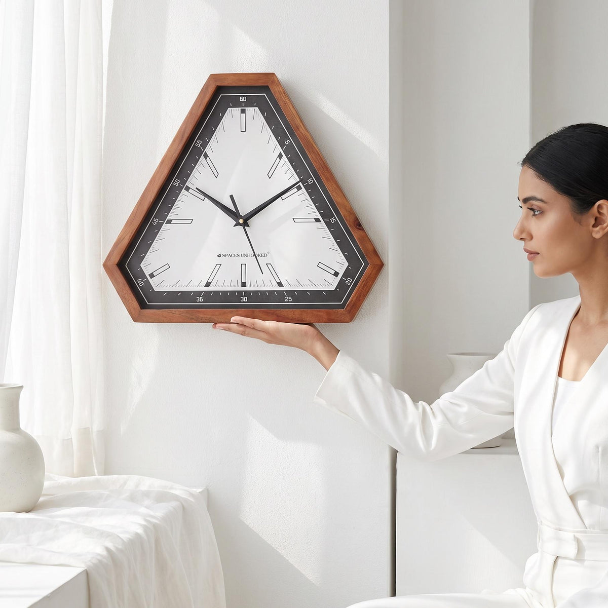 Triangular wooden wall clock with black bezel above a work desk in a modern home office