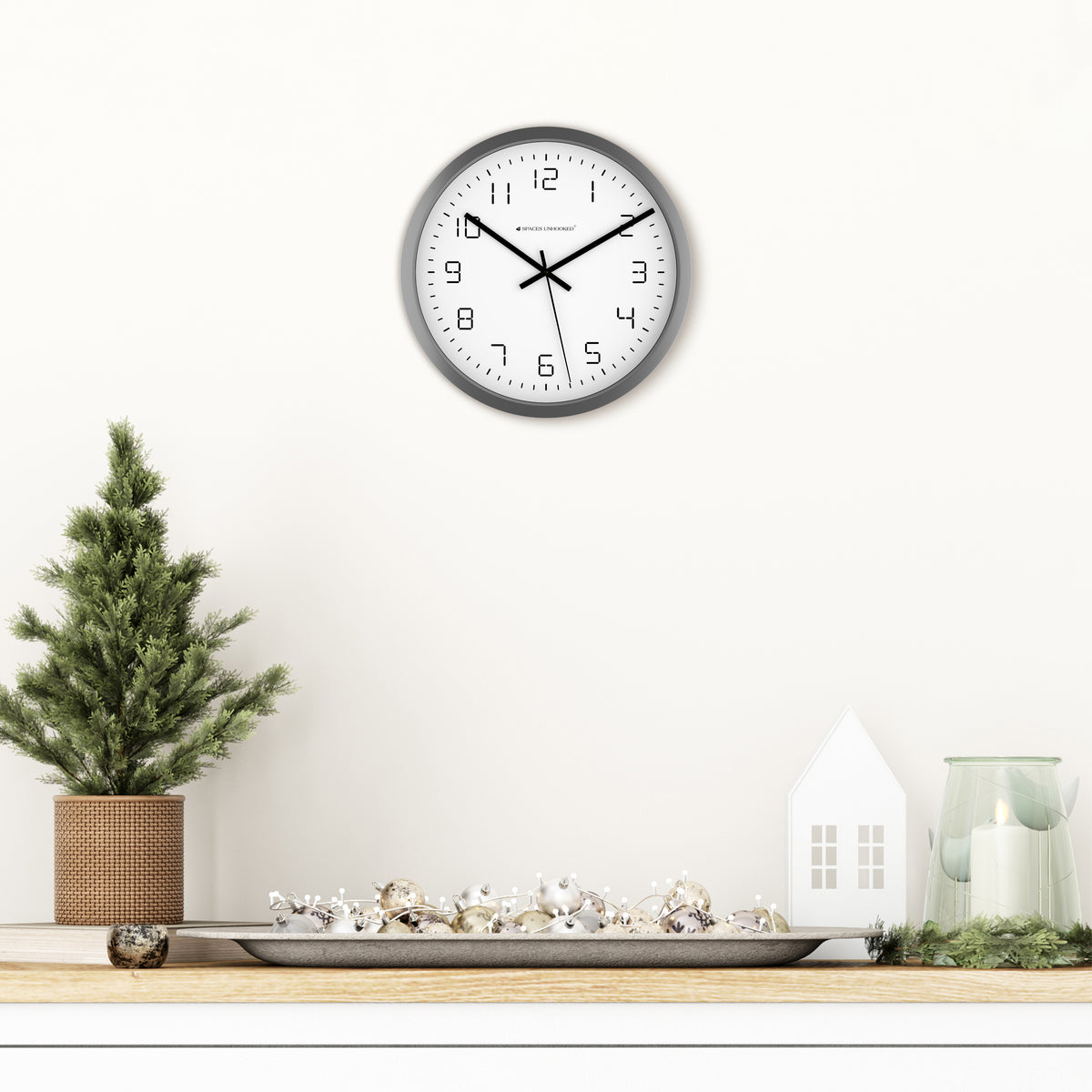 Wall clock on a white wall with decorative items below