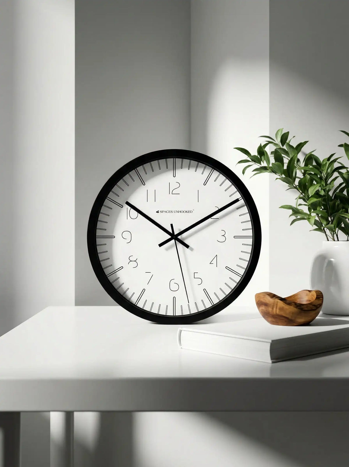 Side angled view of Spaces Unhooked black minimalist wall clock with slim polycrafted frame