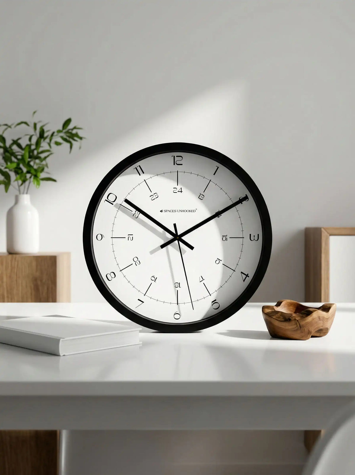 Spaces Unhooked black silent wall clock displayed in a modern living room with minimalist home décor