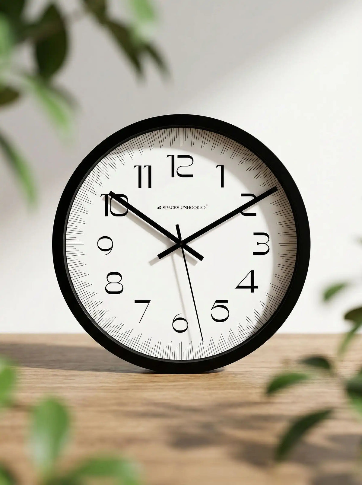 Spaces Unhooked black silent wall clock displayed in a modern living room with elegant home décor