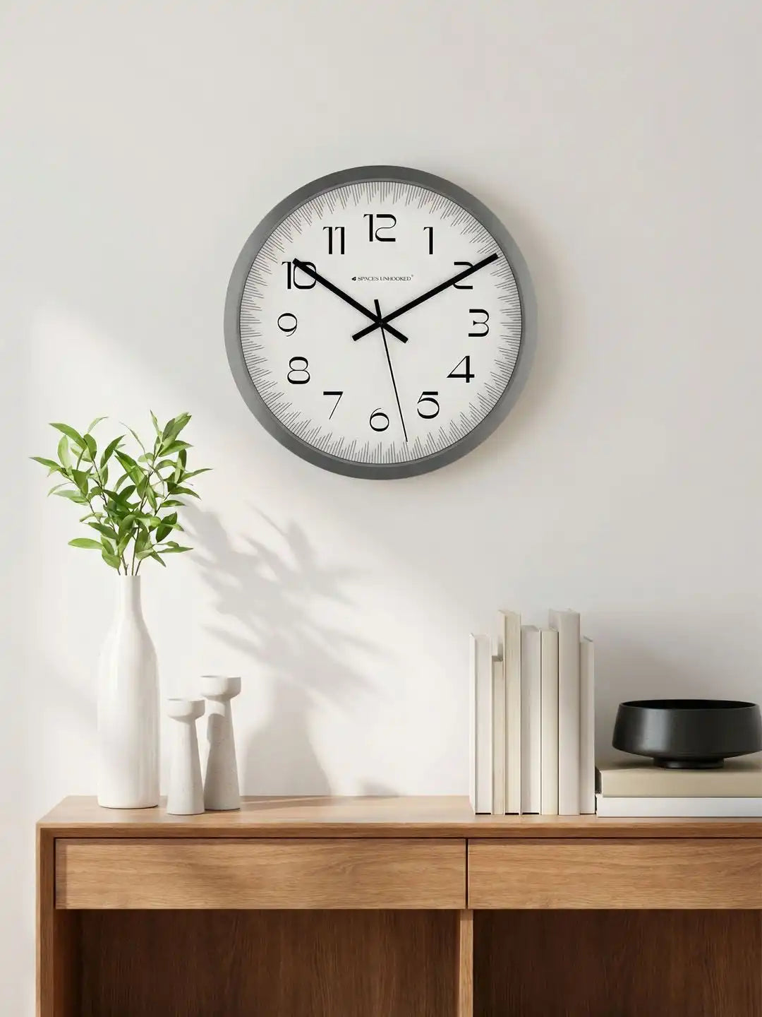 Spaces Unhooked grey silent wall clock displayed on a modern living room wall with minimalist décor