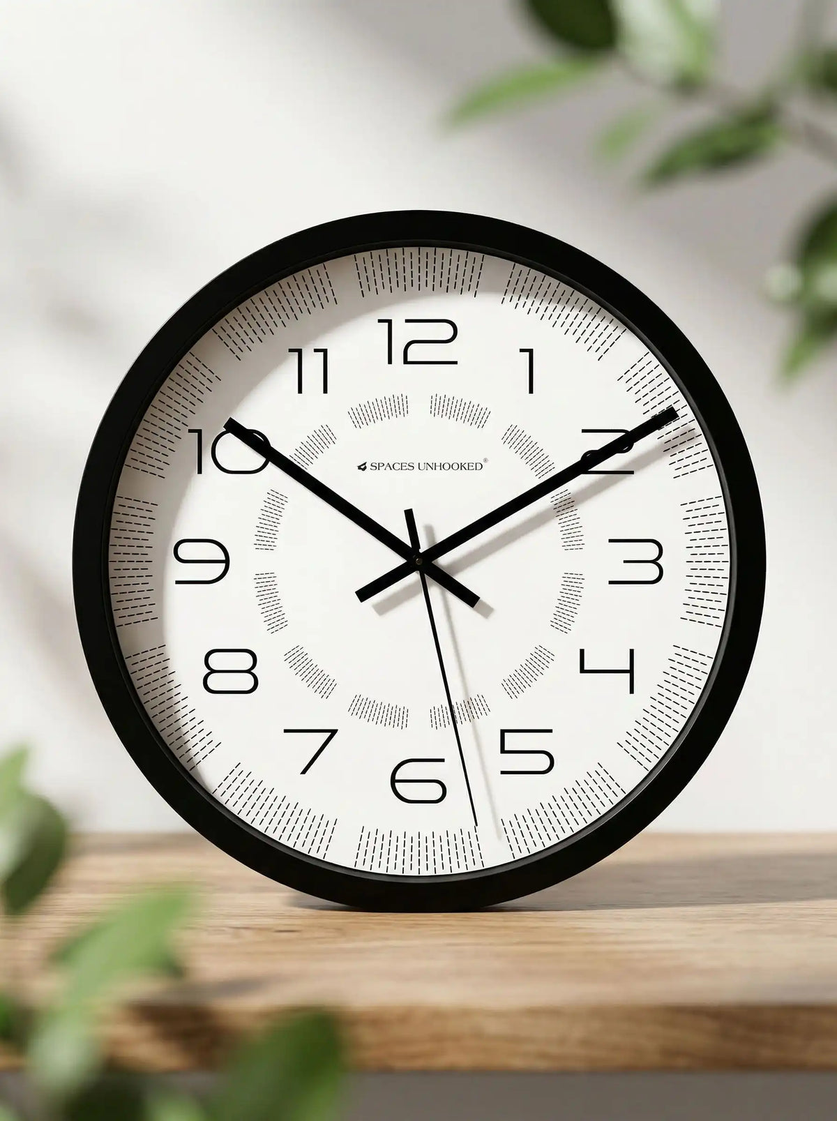 Lifestyle AI View – Premium Silent Black Wall Clock on Wooden Shelf with Green Foliage Decor