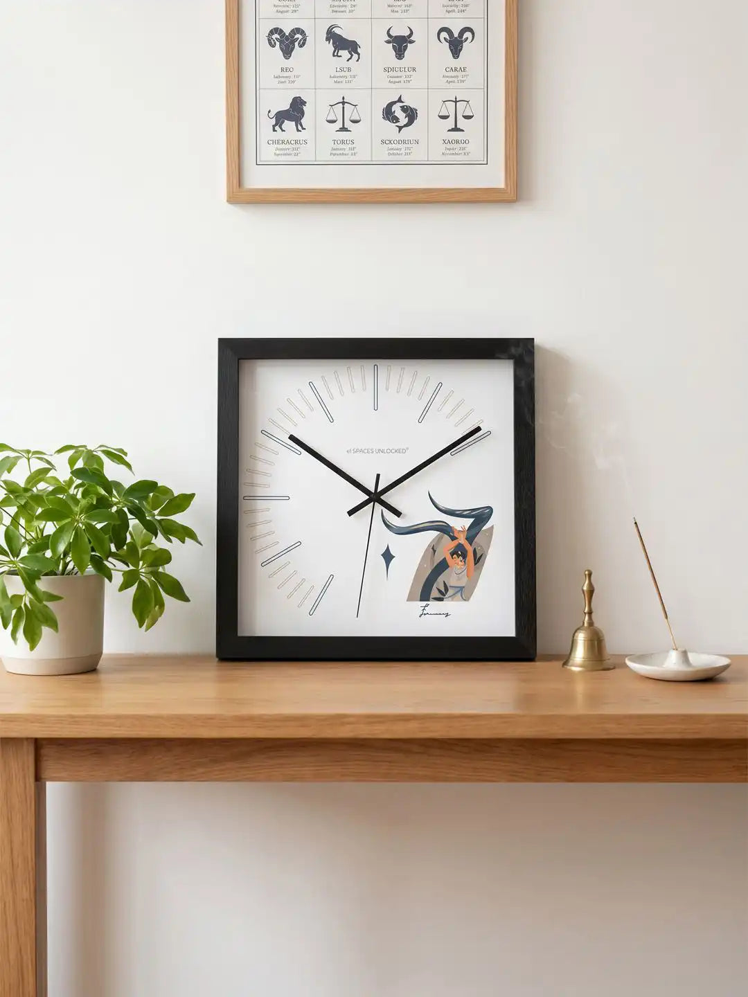 Front view of a square black-framed wall clock with modern hour markers and a decorative dancer artwork in the lower-right corner.