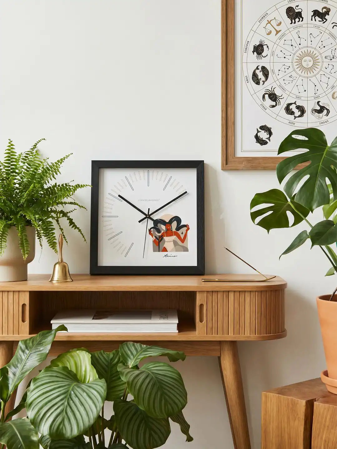 Taurus zodiac wall clock with a black wooden frame, white face, minimalist index markers, and an artistic Taurus illustration in the lower-right corner.