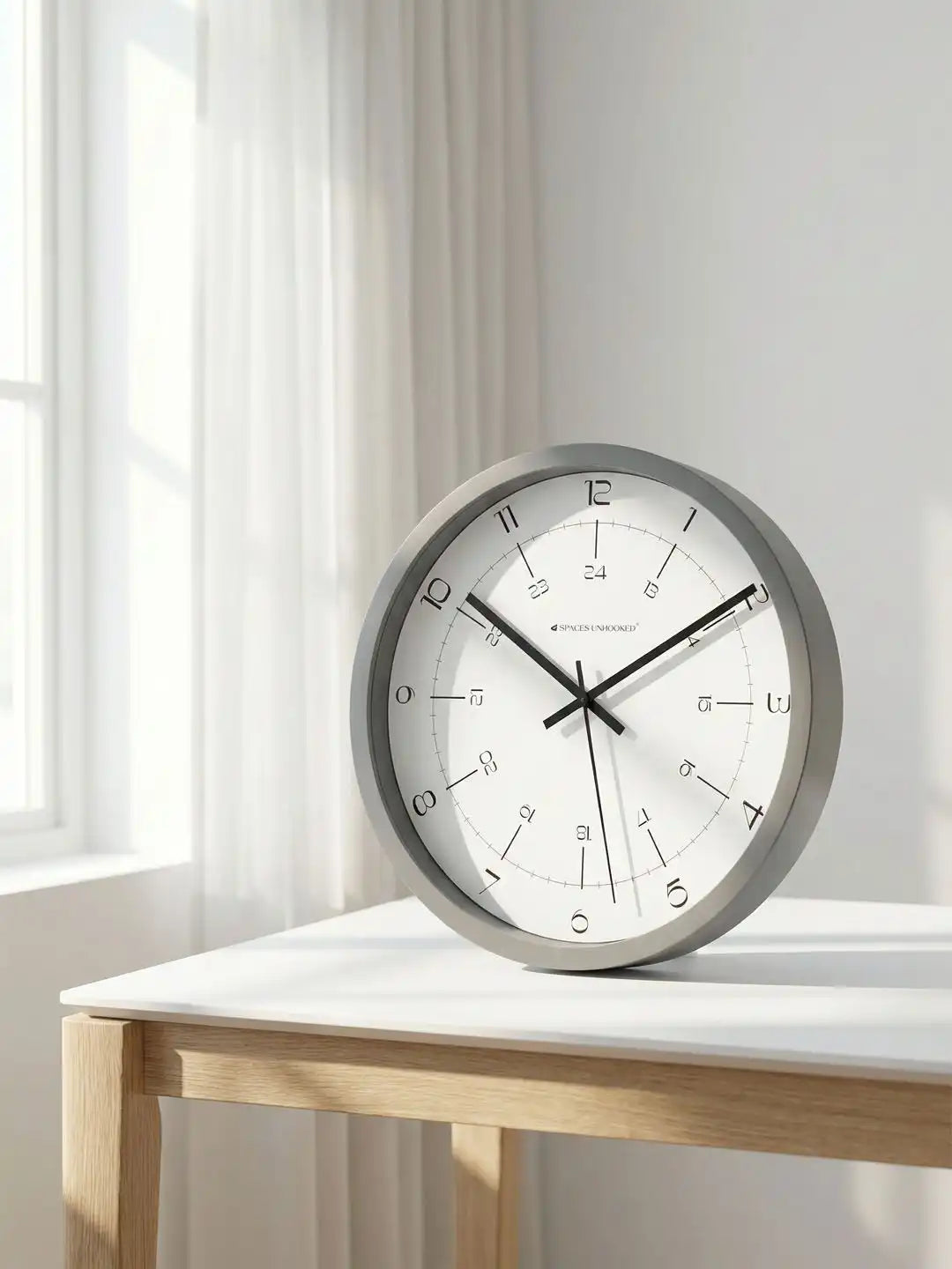 Spaces Unhooked grey contemporary wall clock styled on a tabletop in a bright modern interior