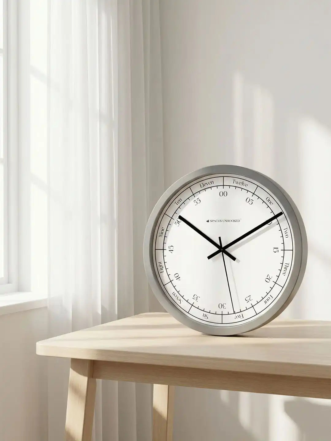 Lifestyle Wall Clock on Wooden Table – Grey Frame Word Hour Minute Dial Designer Wall Clock