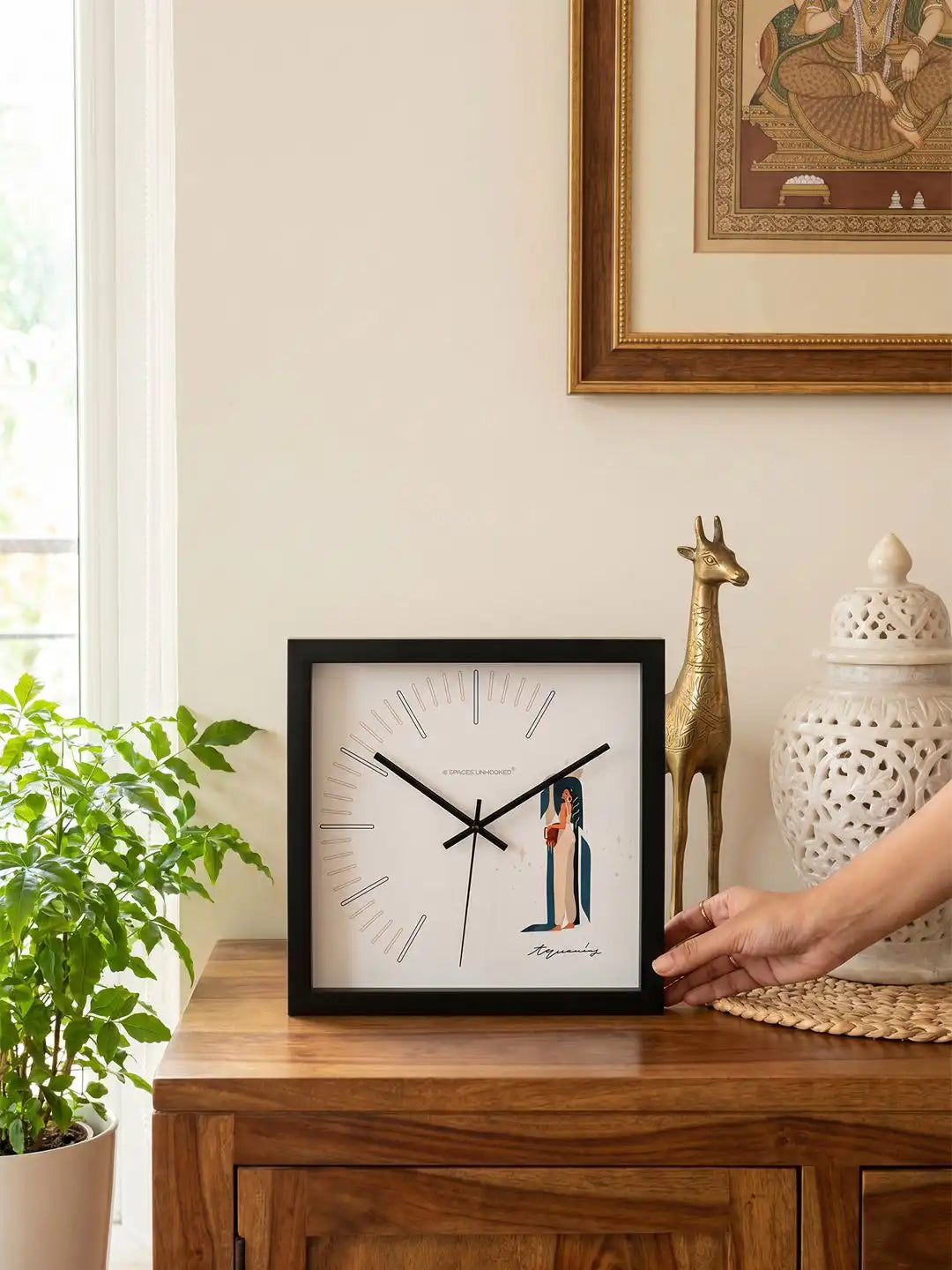 Aquarius zodiac wall clock displayed alongside branded Spaces Unhooked packaging box, featuring a minimalist square design and black wooden frame.