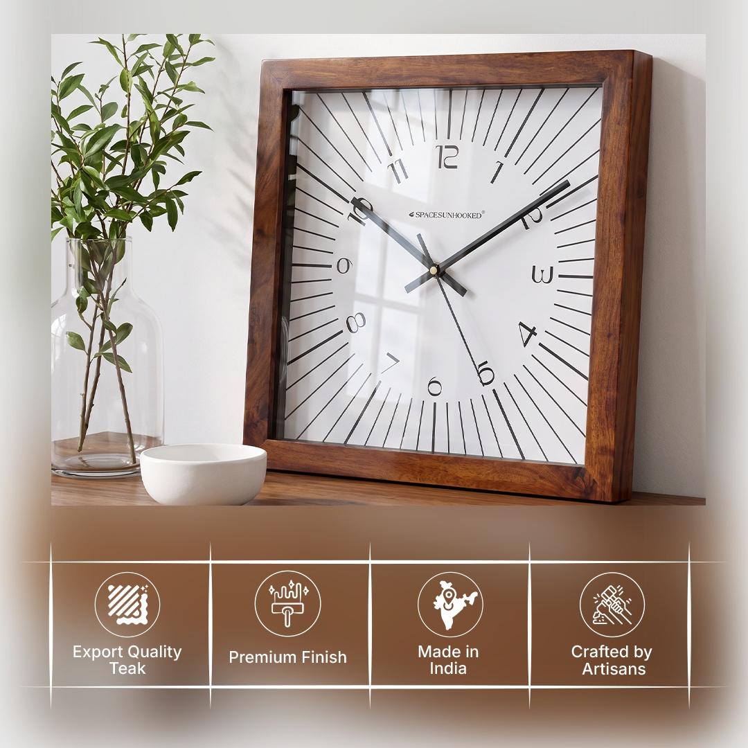 Square wooden wall clock on a hallway wall with geometric rugs and brass accents