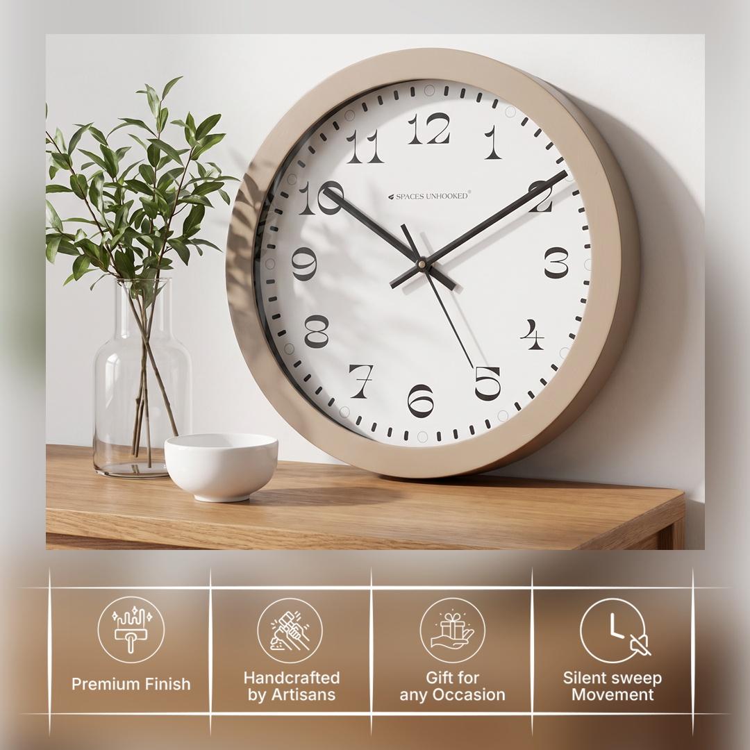 Taupe round wall clock in a bedroom or hallway with soft green plants and ceramics