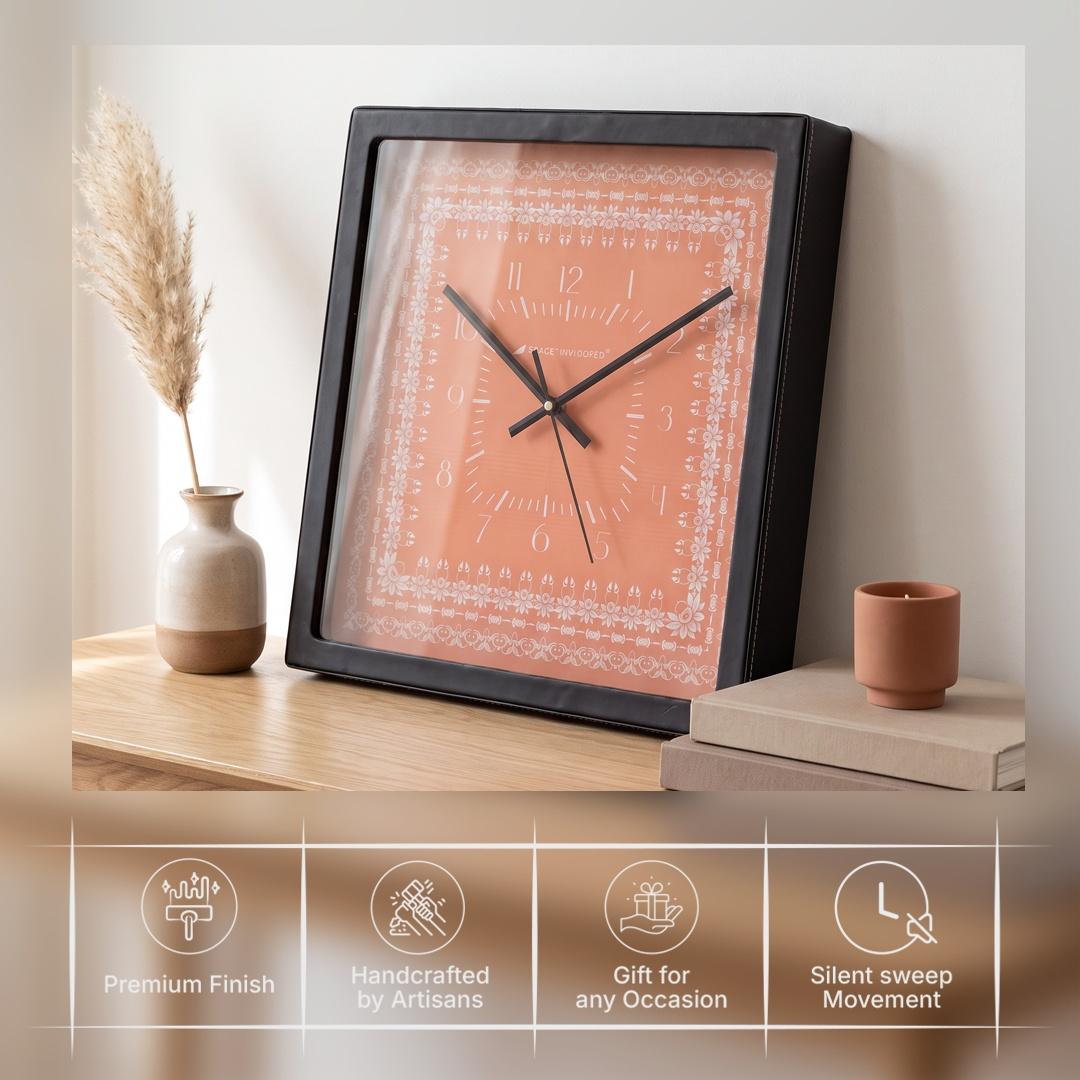 Black hour and minute hands over slim numerals on a coral clock dial