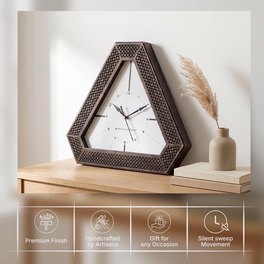 Triangular bronze wall clock on a study wall above a desk