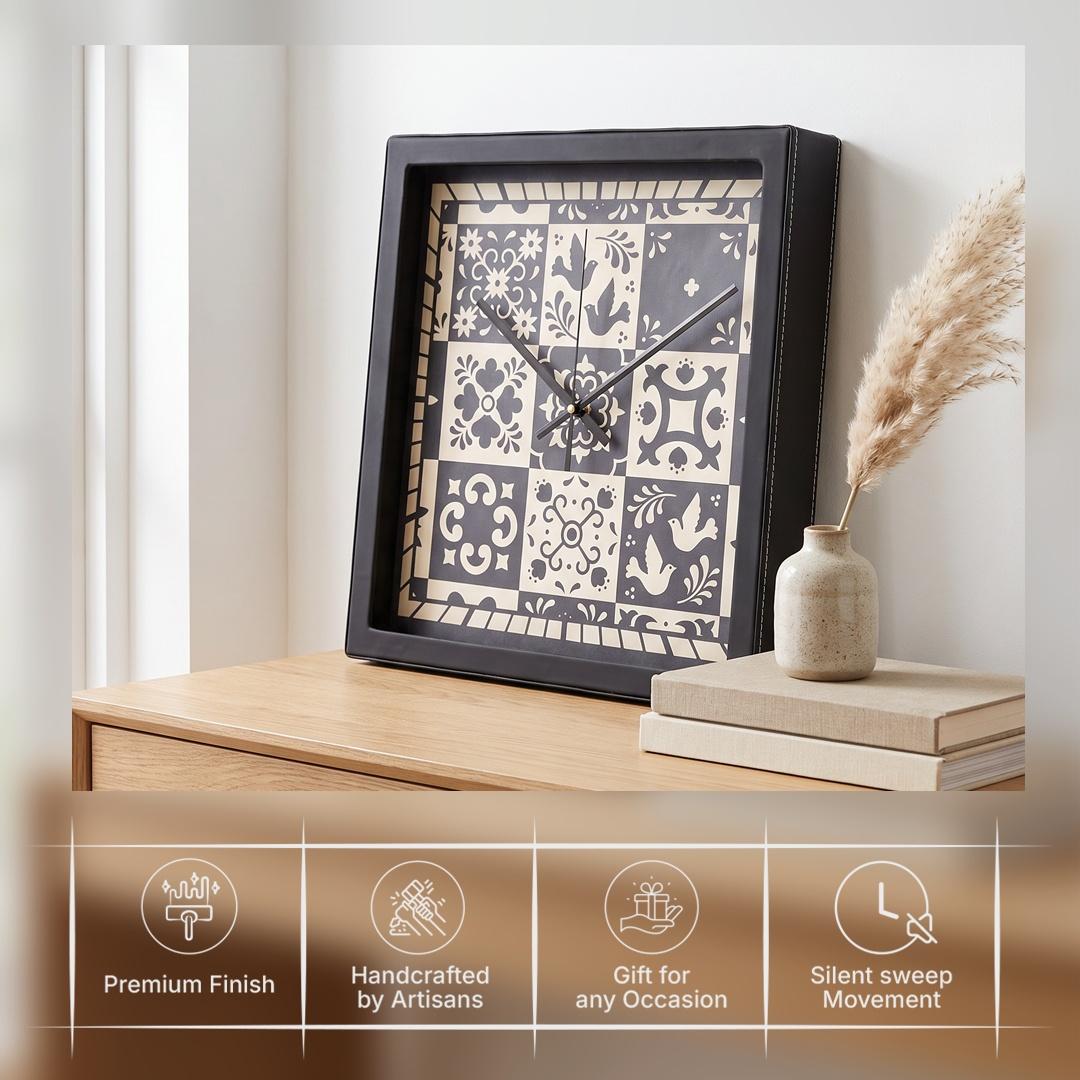 Slim black hands over black and cream tile motifs on a folk art clock dial