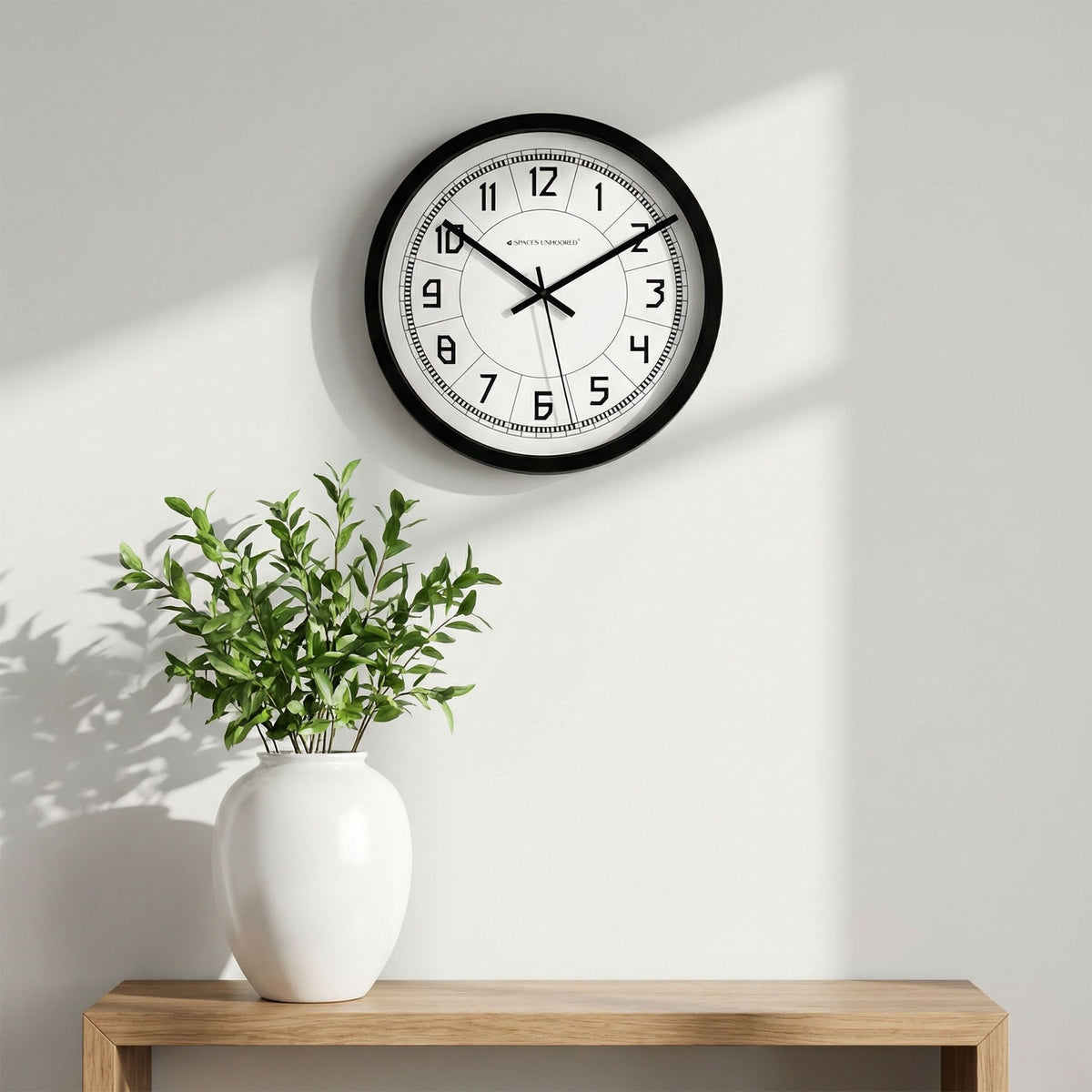 Spaces Unhooked round wall clock black frame bold numerals segmented white dial – silent quartz wall clock living room India