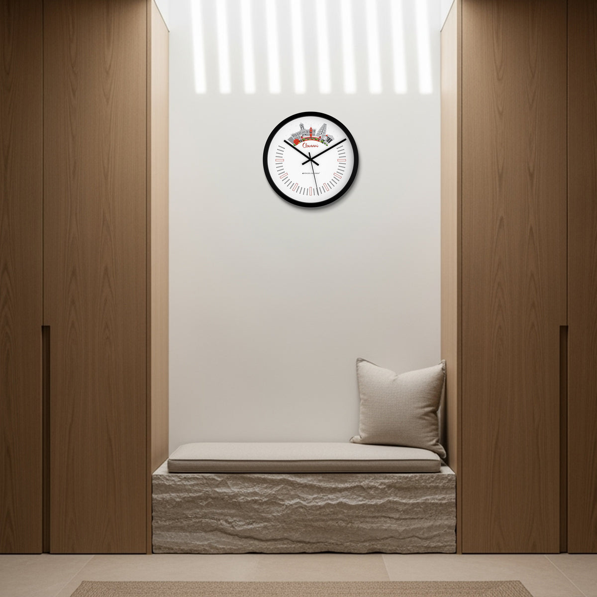 Wall clock on a white wall above a cushioned bench with wooden panels on either side.