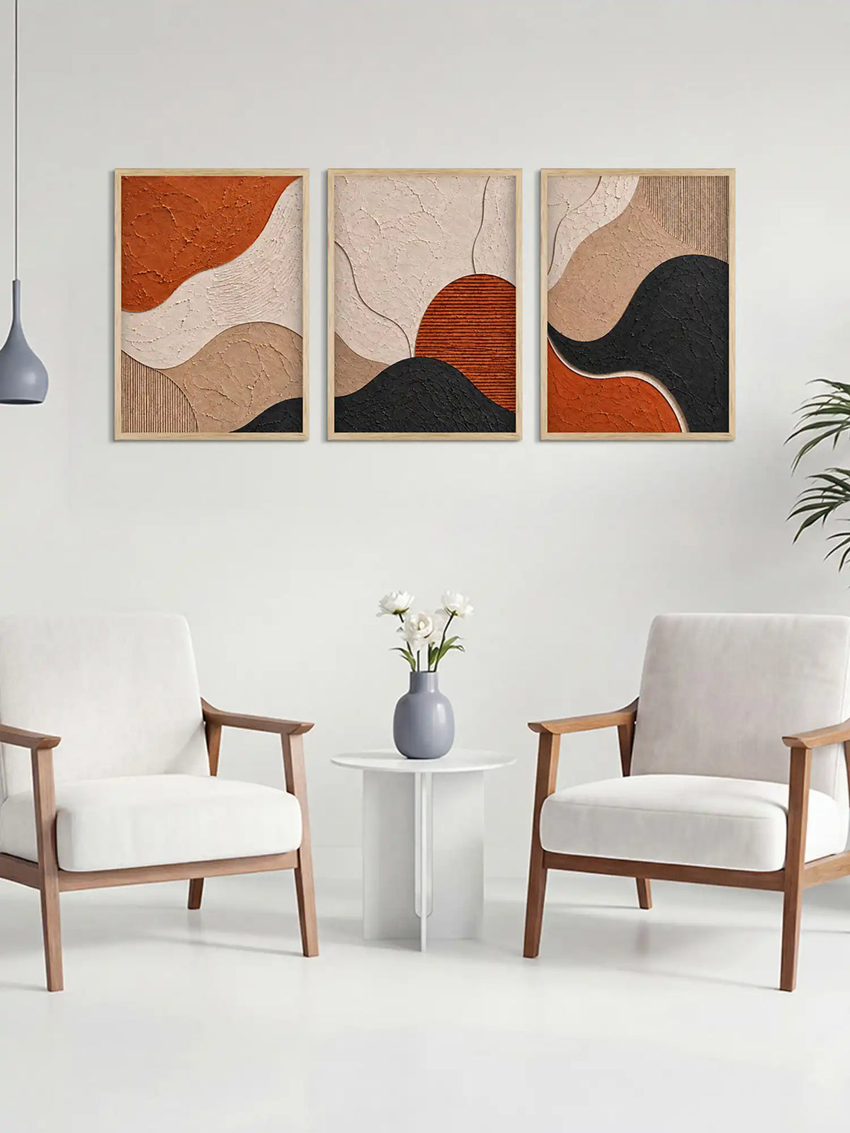 Three abstract art pieces on a wall above a small table with a vase and flowers, flanked by two chairs.
