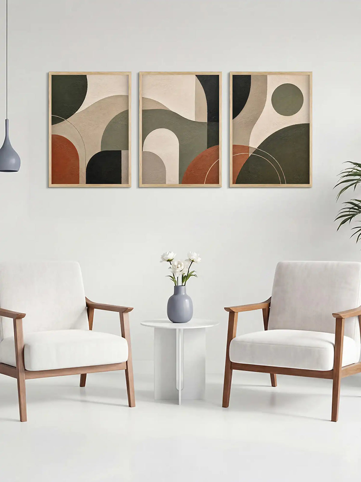 Three abstract art pieces on a wall above a table with a vase and flowers, flanked by two chairs.